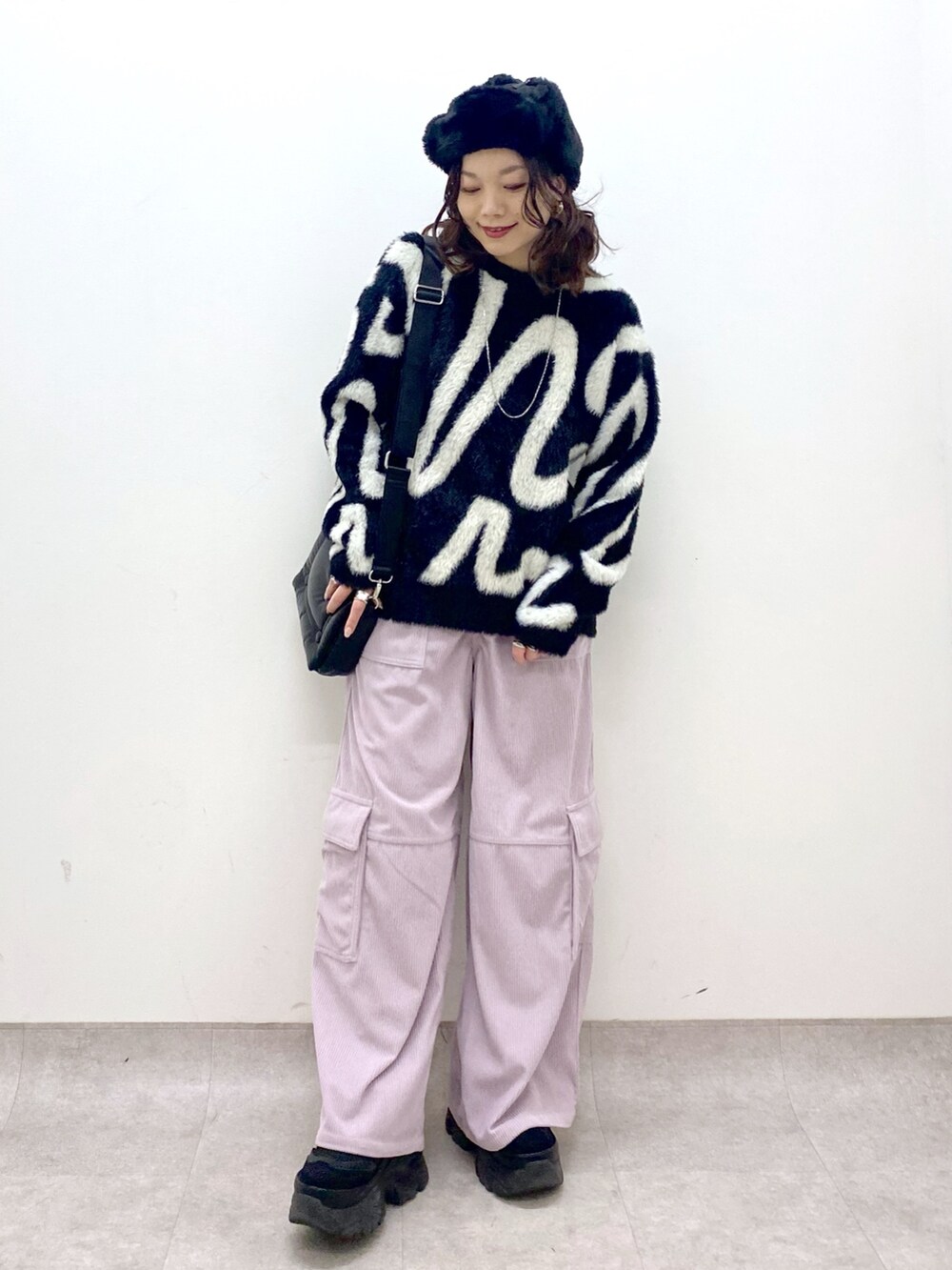 ピンク系のカーゴパンツ、ブラック系のニット/セーター、ブラック系のショルダーバッグを着用したレディースの冬コーディネートの9枚目の写真