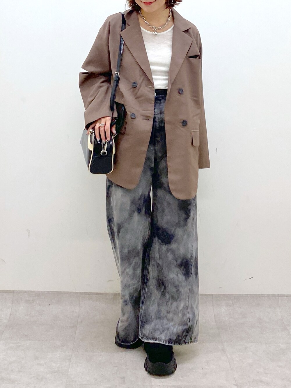 ブラック系のデニムパンツ、ブラック系のスニーカー、ブラウン系のテーラードジャケットを着用したレディースの秋コーディネートの3枚目の写真