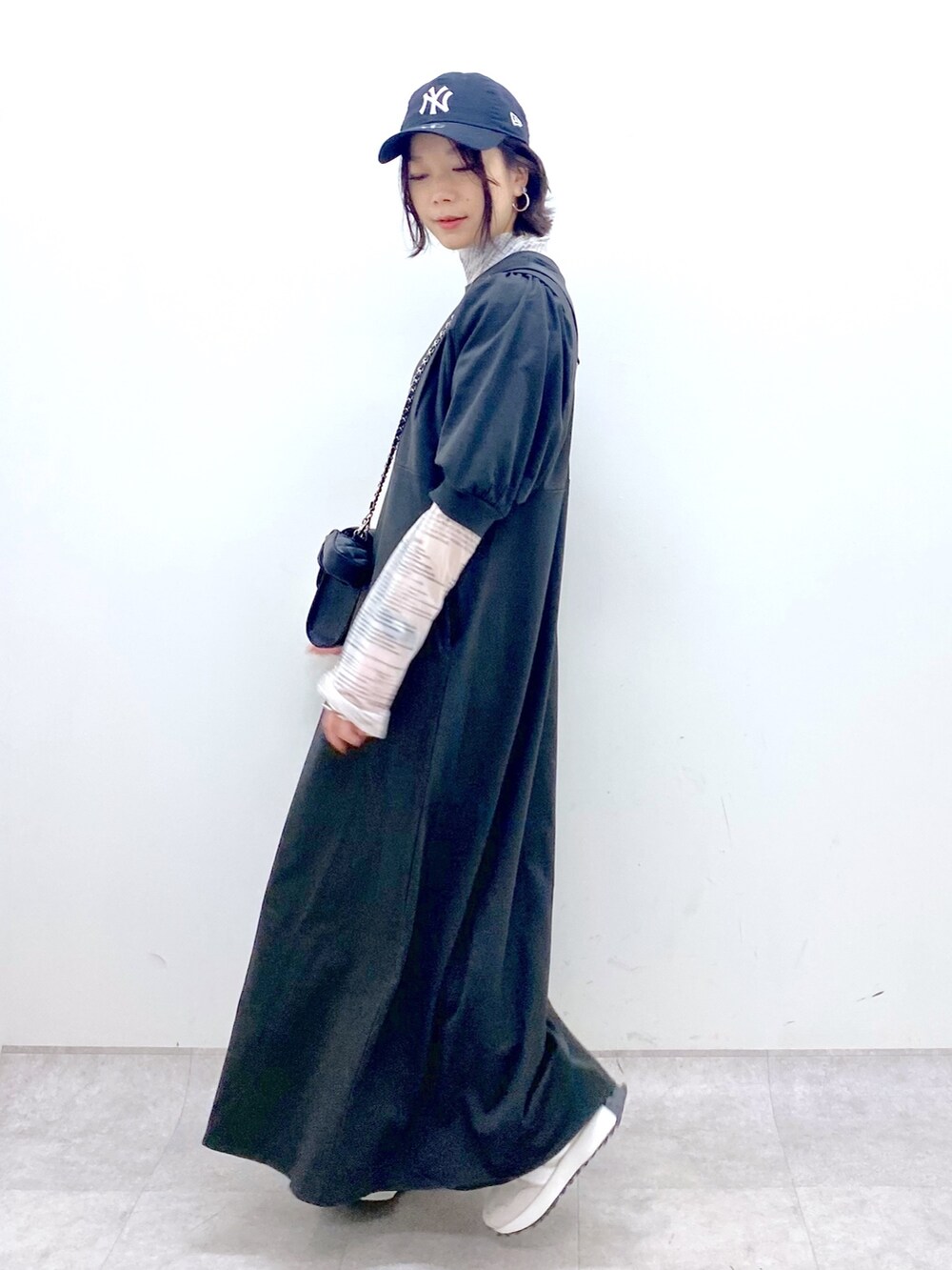 ブラック系のワンピース、ベージュ系のスニーカー、ブラック系のバッグを着用したレディースの春コーディネートの2枚目の写真