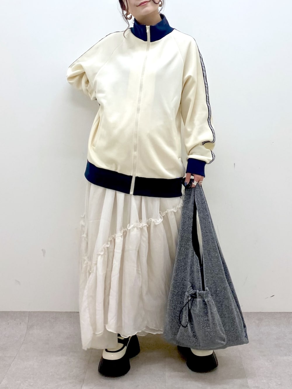 ホワイト系のセットアップ、ブラック系のトートバッグ、ホワイト系のスカートを着用したレディースの冬コーディネートの3枚目の写真