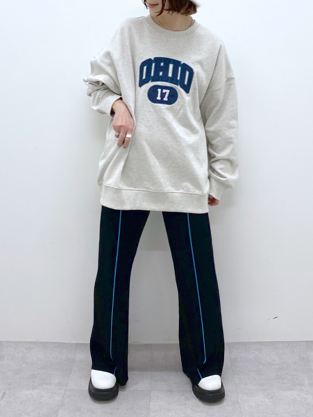 ベージュ系のトップス、ブラック系のパンツ、ホワイト系のシューズを着用したレディースの秋コーディネートの5枚目の写真