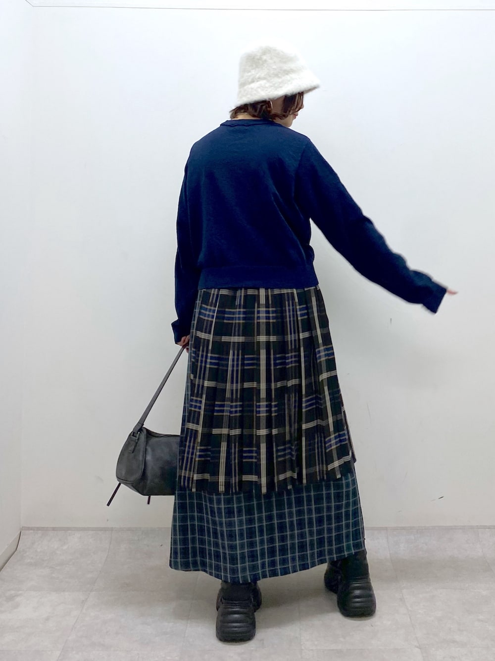 ブルー系のニット/セーター、ブルー系のスカート、ブラック系のショルダーバッグを着用したレディースの秋コーディネートの6枚目の写真