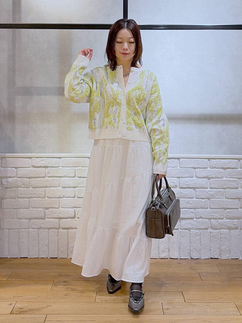 グレー系のショルダーバッグ、ブラウン系のサンダル、ホワイト系のスカートを着用したレディースの冬コーディネートの8枚目の写真