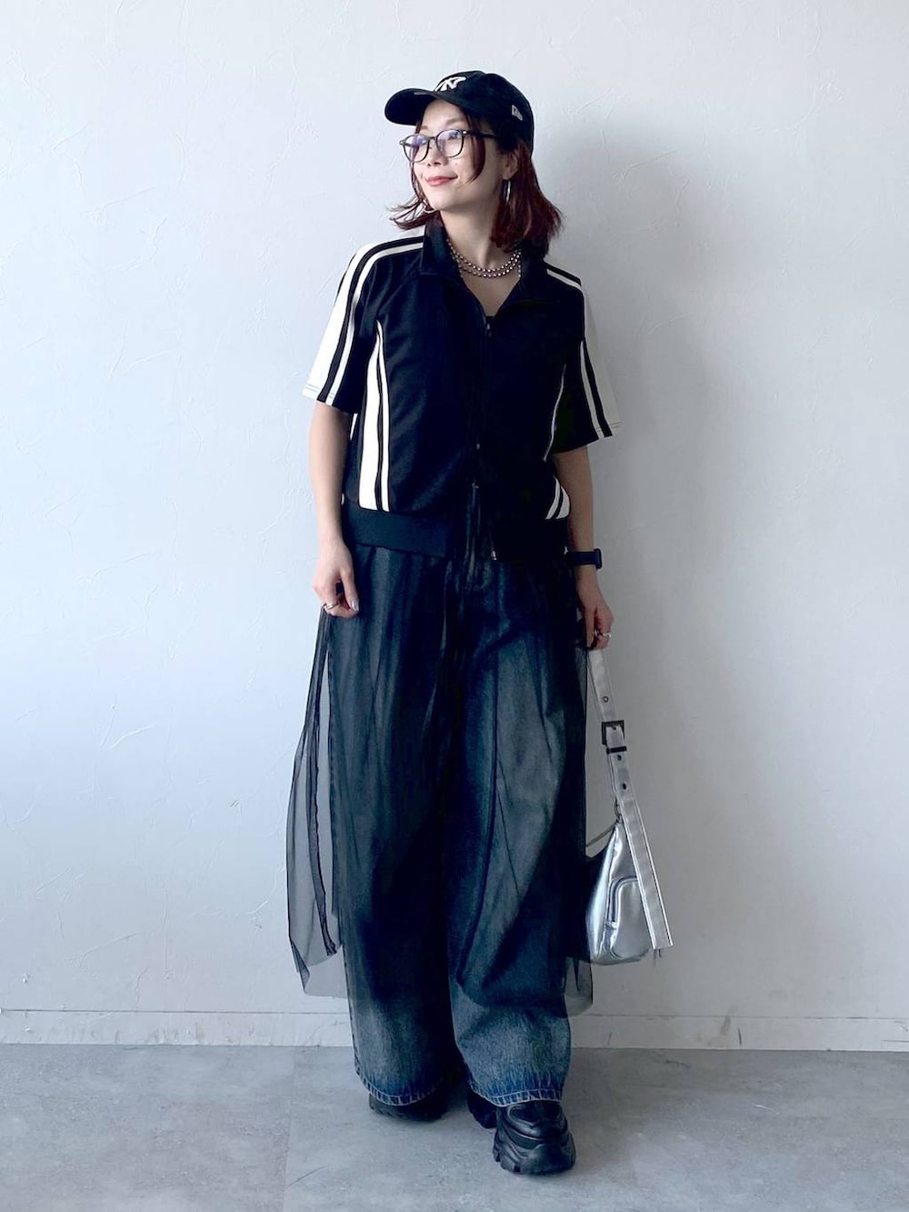 ブラック系のスニーカー、シルバー系のショルダーバッグ、ブルー系のデニムパンツを着用したレディースの夏コーディネートの4枚目の写真