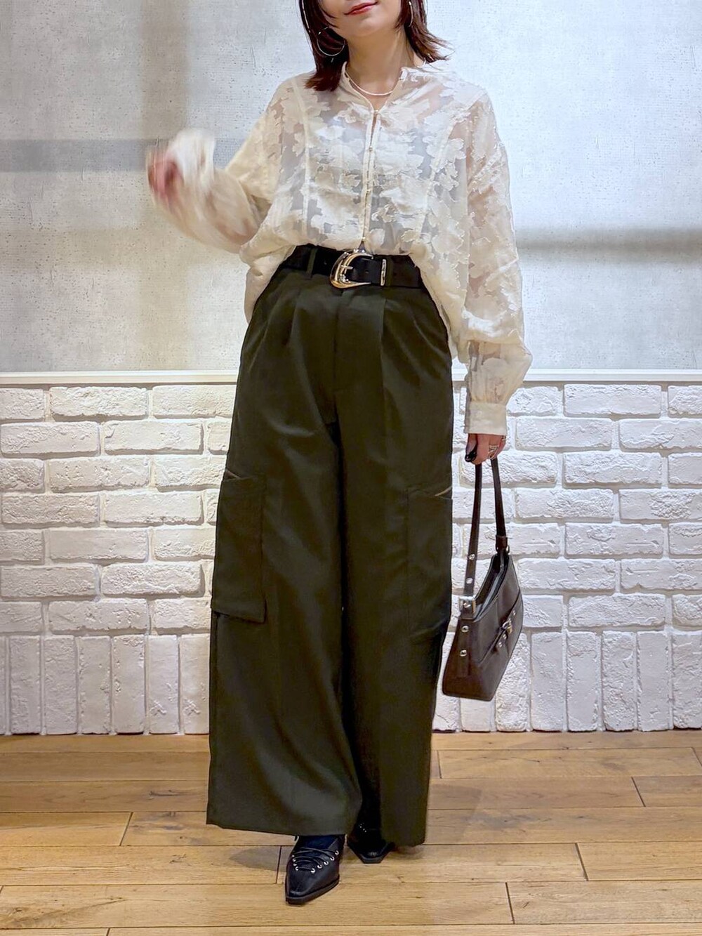 ブラウン系のハンドバッグ、グリーン系のスラックス、ホワイト系のTシャツ/カットソーを着用したレディースの冬コーディネートの2枚目の写真