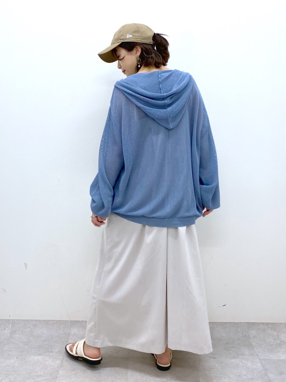 ベージュ系のジャンパースカート、ブルー系のニット/セーター、ブラック系のキャミソールを着用したレディースの夏コーディネートの3枚目の写真