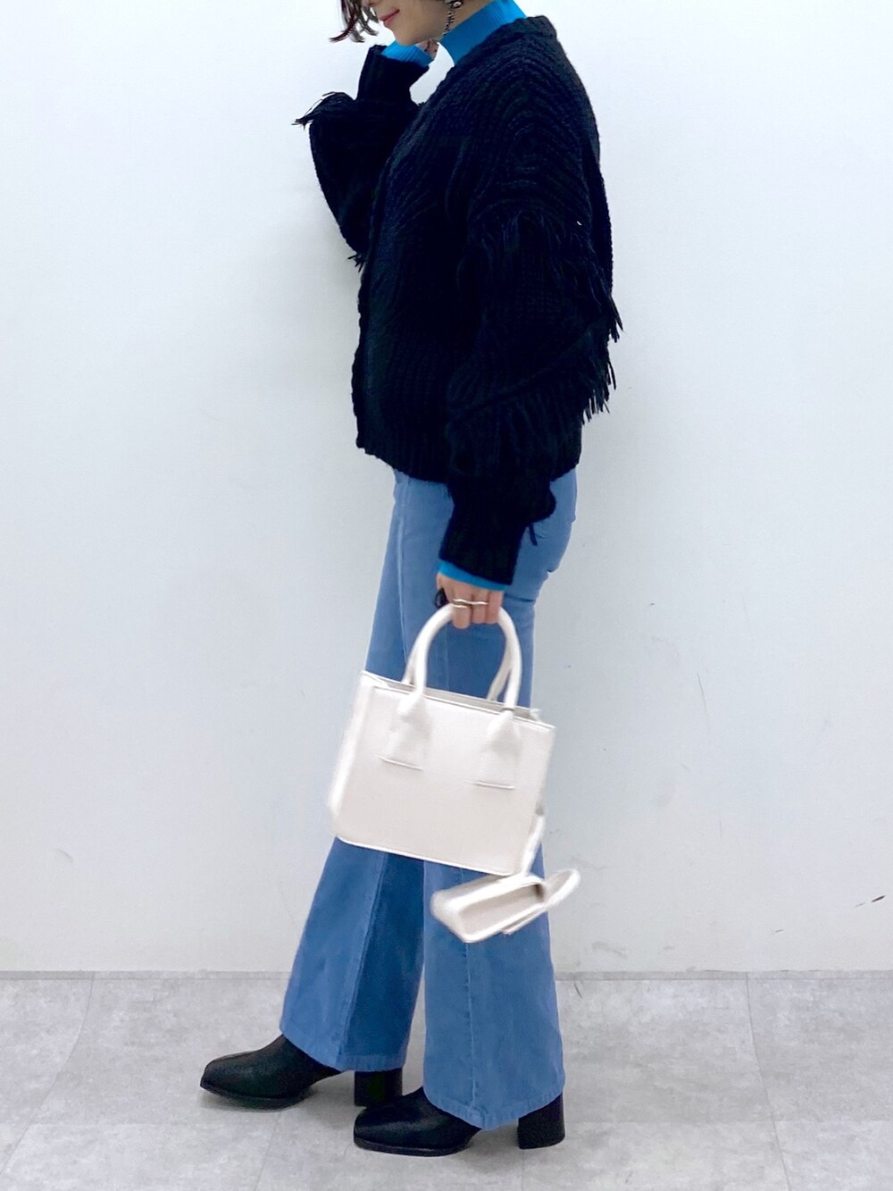 ブルー系のパンツ、ホワイト系のバッグ、ブラック系のシューズを着用したレディースの秋コーディネートの3枚目の写真
