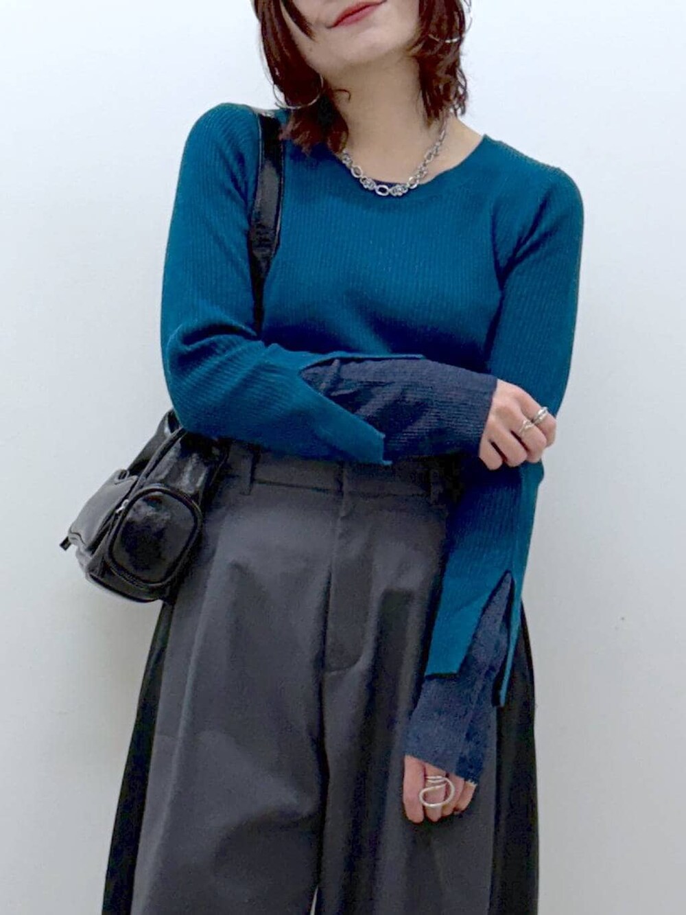 ブラック系のブーツ、グリーン系のニット/セーター、ブラック系のショルダーバッグを着用したレディースの冬コーディネートの2枚目の写真