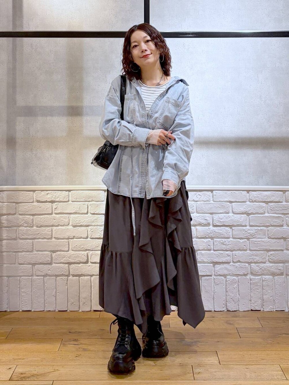 ブラック系のブーツ、ブラック系のショルダーバッグ、グレー系のスカートを着用したレディースの冬コーディネートの9枚目の写真