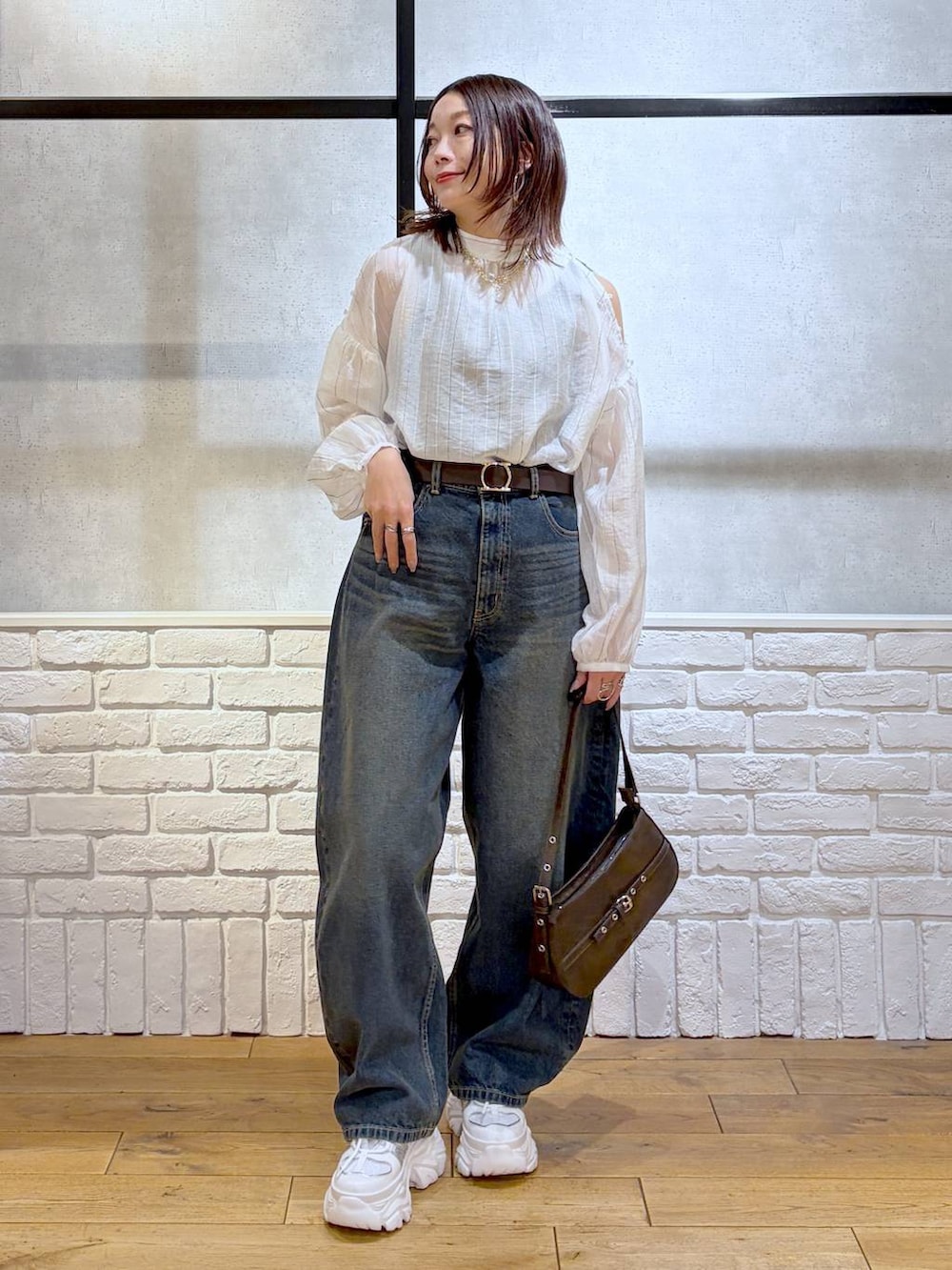 ホワイト系のスニーカー、ブルー系のデニムパンツ、ブラウン系のハンドバッグを着用したレディースの春コーディネートの8枚目の写真
