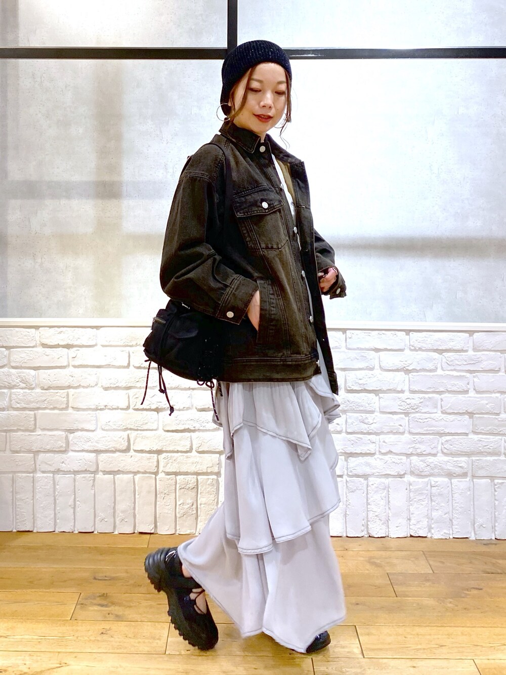 ブラック系のデニムジャケット、グレー系のスカート、ブラック系のスニーカーを着用したレディースの春コーディネートの7枚目の写真