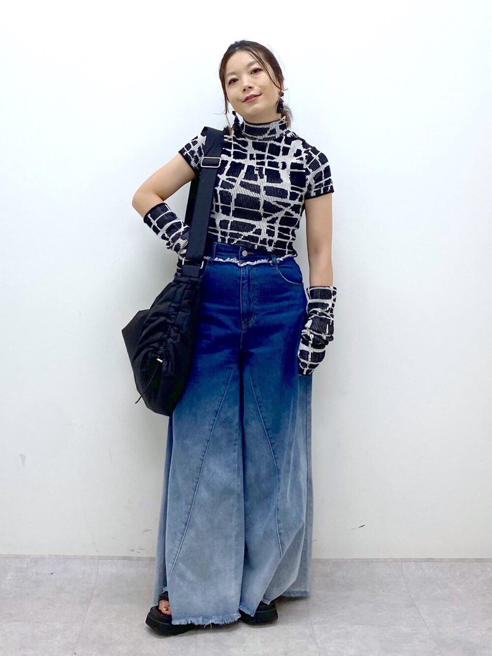 ブルー系のデニムパンツ、ブラック系のニット/セーター、ブラック系のショルダーバッグを着用したレディースの夏コーディネートの9枚目の写真