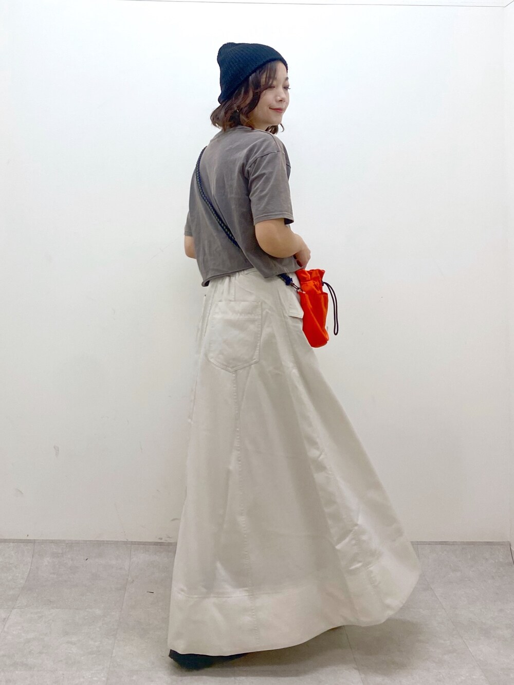 ブラック系のTシャツ/カットソー、オレンジ系のショルダーバッグ、ベージュ系のスカートを着用したレディースの夏コーディネートの6枚目の写真