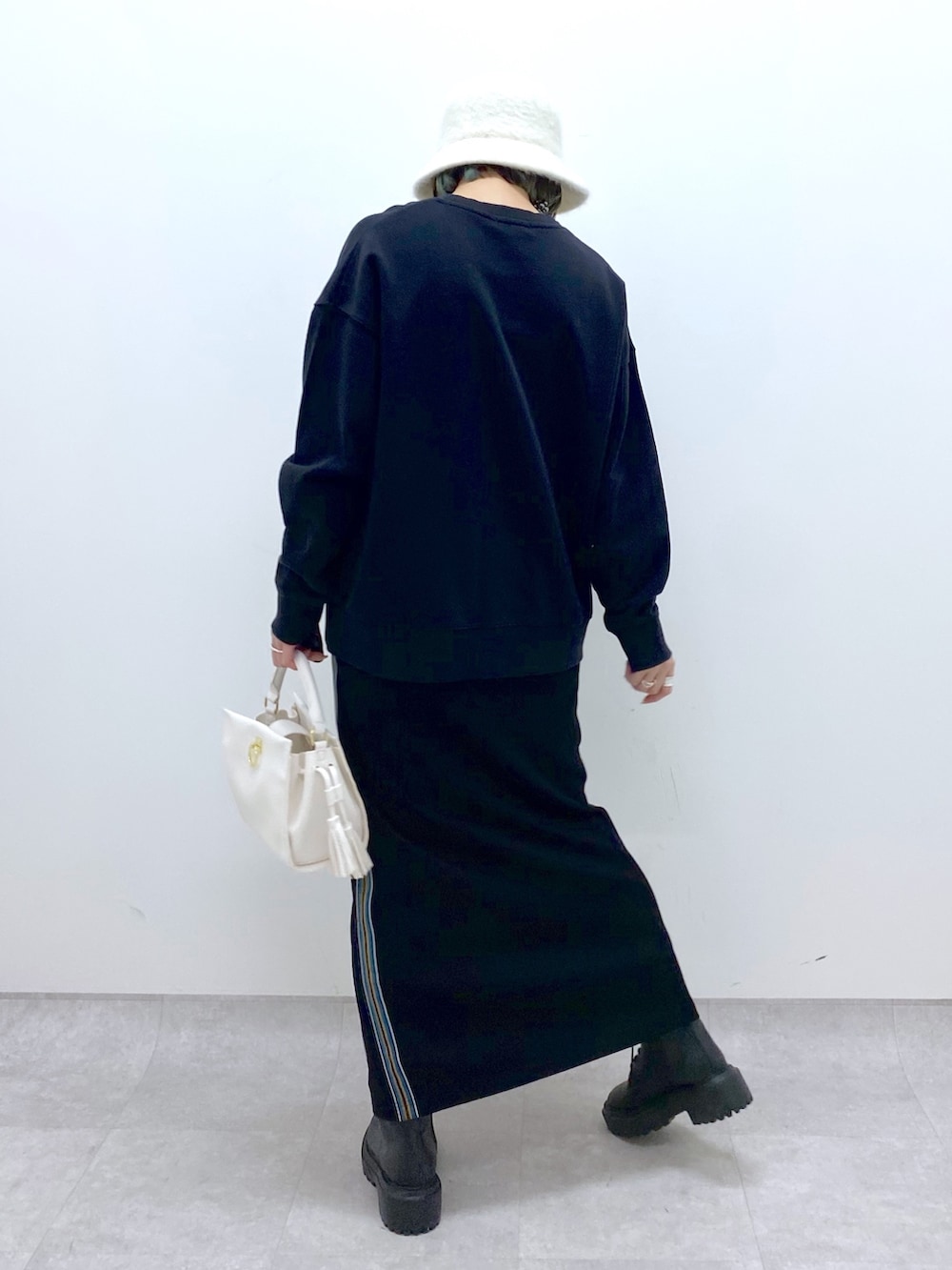 ブラック系のTシャツ/カットソー、ブラック系のスカート、ホワイト系のショルダーバッグを着用したレディースの冬コーディネートの3枚目の写真