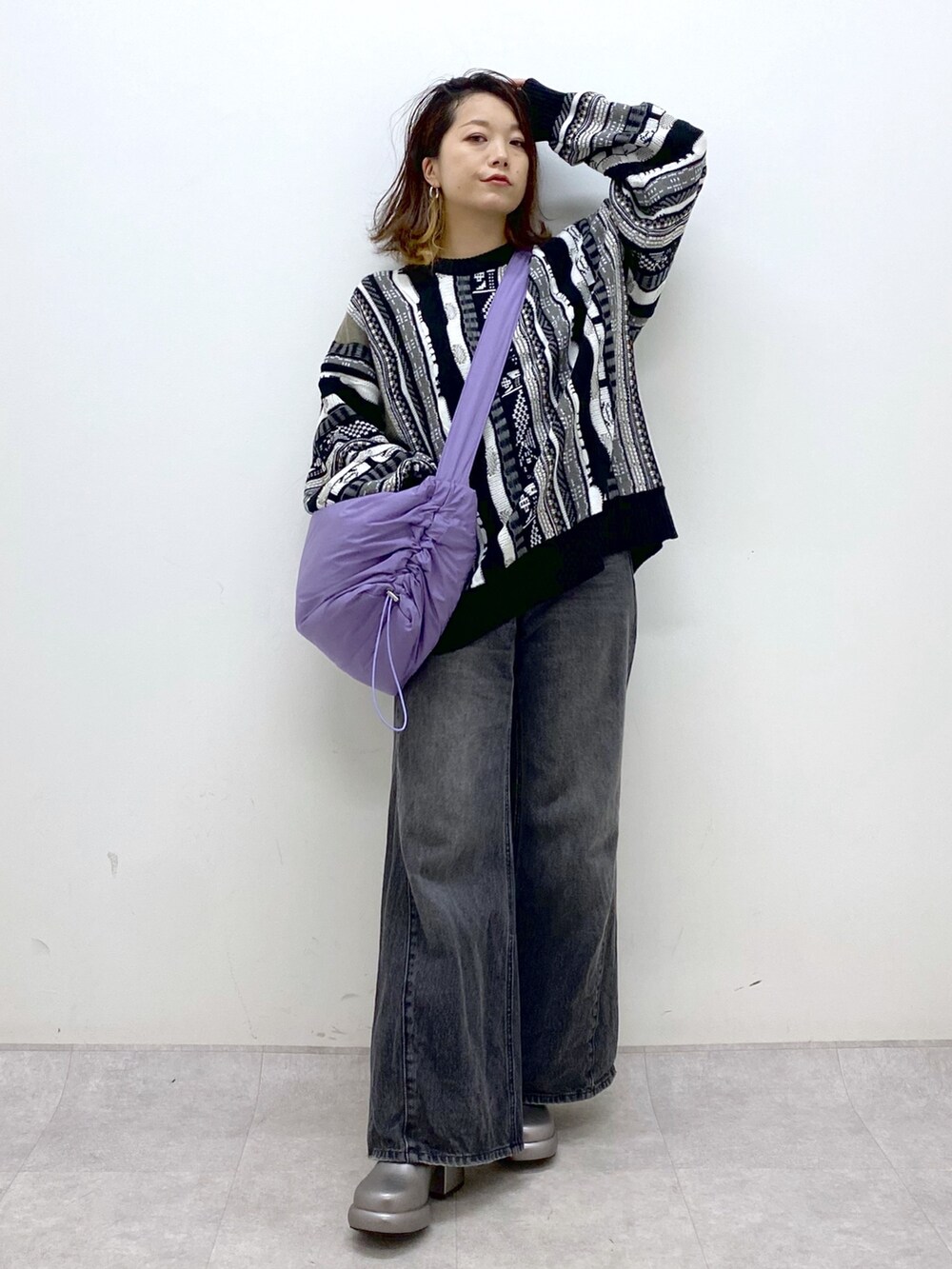 ブラック系のニット/セーター、ブラック系のデニムパンツ、パープル系のショルダーバッグを着用したレディースの秋コーディネートの9枚目の写真