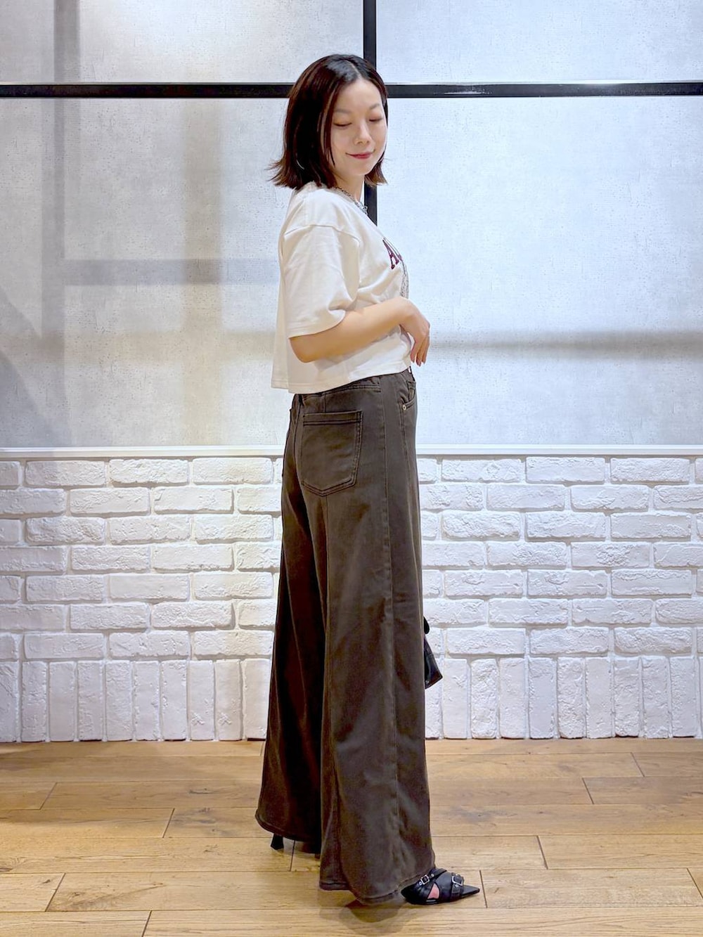 ブラウン系のデニムパンツ、ホワイト系のTシャツ/カットソー、ブラック系のサンダルを着用したレディースの夏コーディネートの6枚目の写真