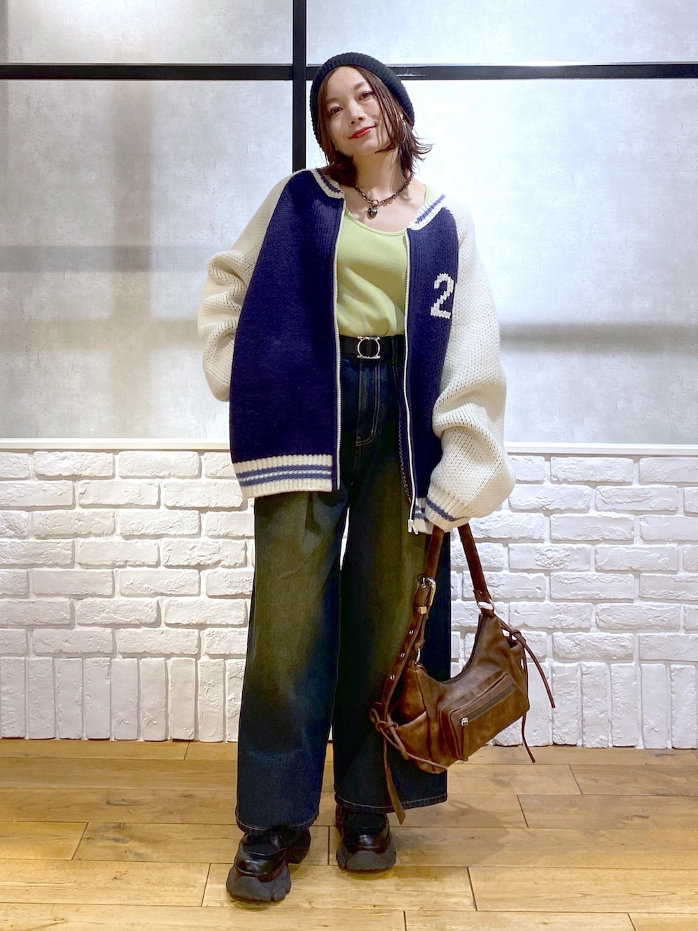 イエロー系のTシャツ/カットソー、ブラウン系のショルダーバッグ、ブルー系のデニムパンツを着用したレディースの冬コーディネートの2枚目の写真