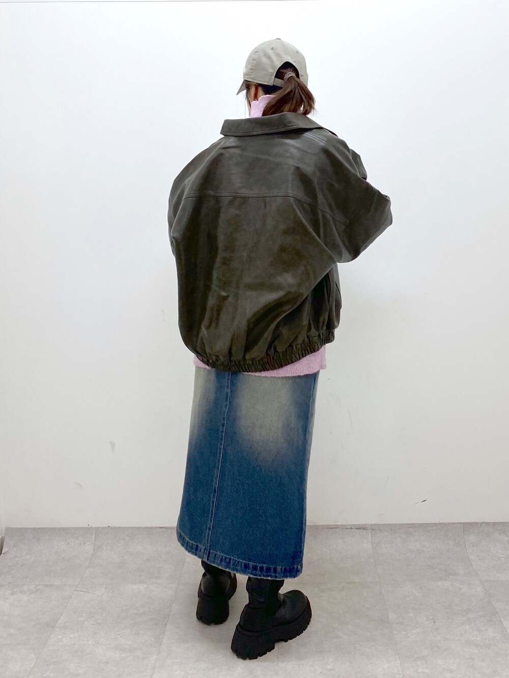 レッド系のニット/セーター、ブルー系のスカート、ブラック系のブーツを着用したレディースの秋コーディネートの3枚目の写真