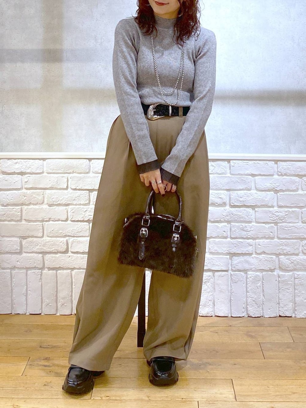 ベージュ系のスラックス、ブラウン系のボストンバッグ、グレー系のニット/セーターを着用したレディースの冬コーディネートの3枚目の写真