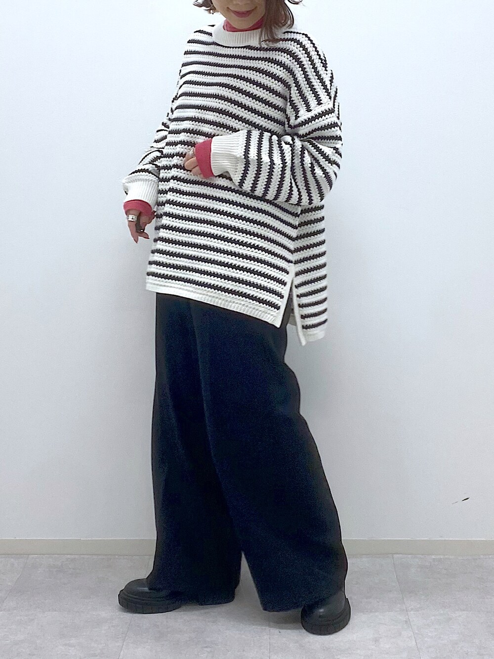 ホワイト系のニット/セーター、ピンク系のTシャツ/カットソー、ブラック系のスラックスを着用したレディースの春コーディネートの5枚目の写真