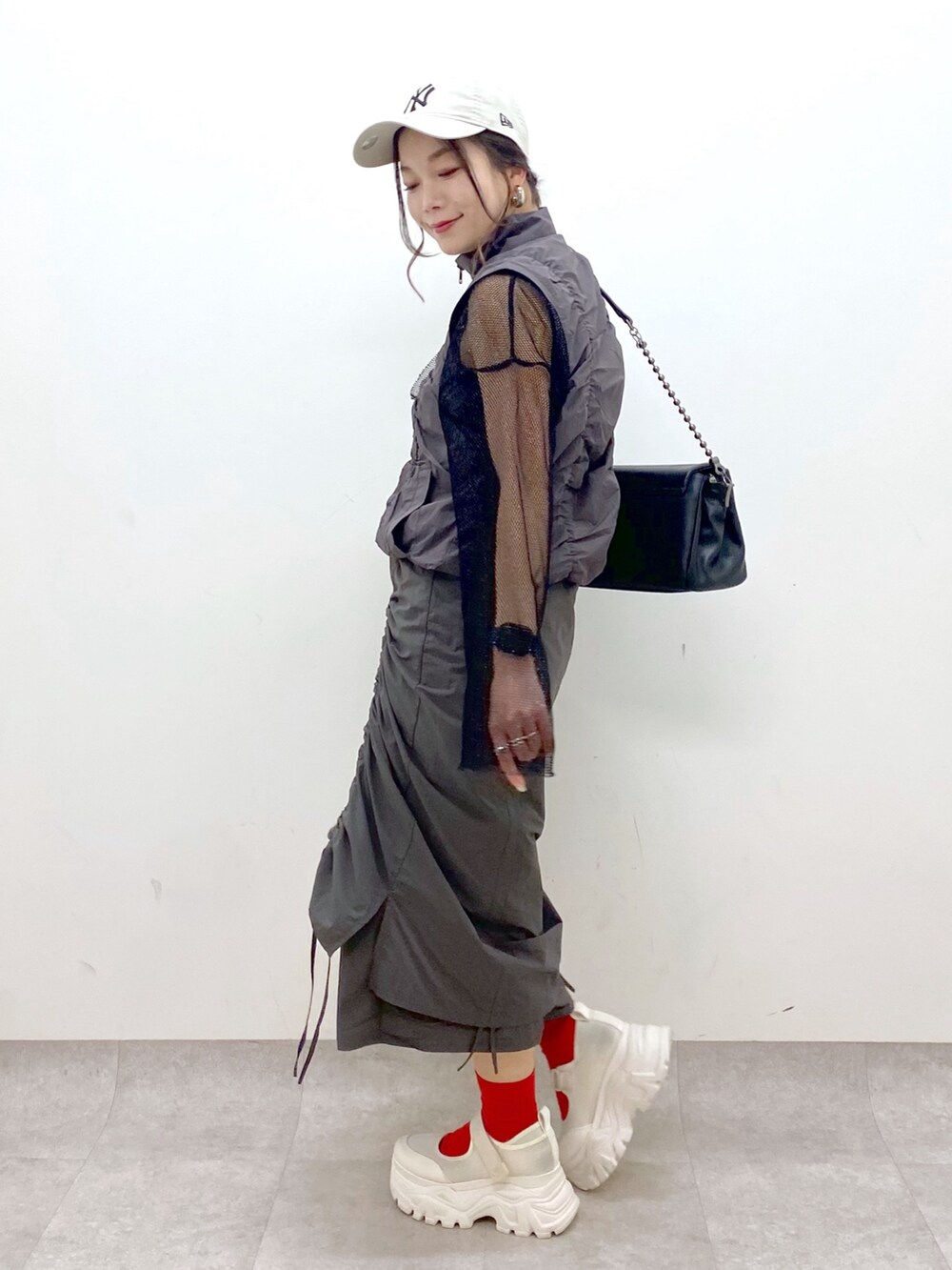 グレー系のスカート、ブラック系のショルダーバッグ、ブラック系のTシャツ/カットソーを着用したレディースの春コーディネートの8枚目の写真