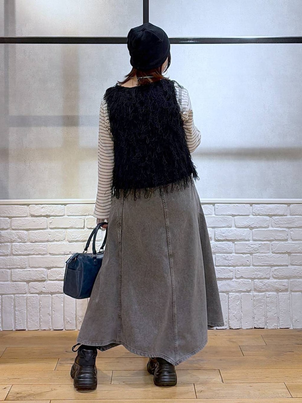 ブラック系のスニーカー、ブラック系のワンピース、ブルー系のショルダーバッグを着用したレディースの冬コーディネートの6枚目の写真