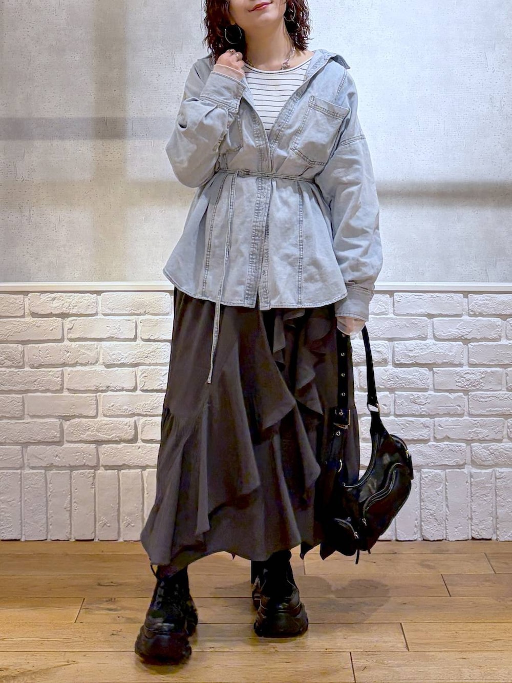 ブラック系のブーツ、ブラック系のショルダーバッグ、グレー系のスカートを着用したレディースの冬コーディネートの3枚目の写真