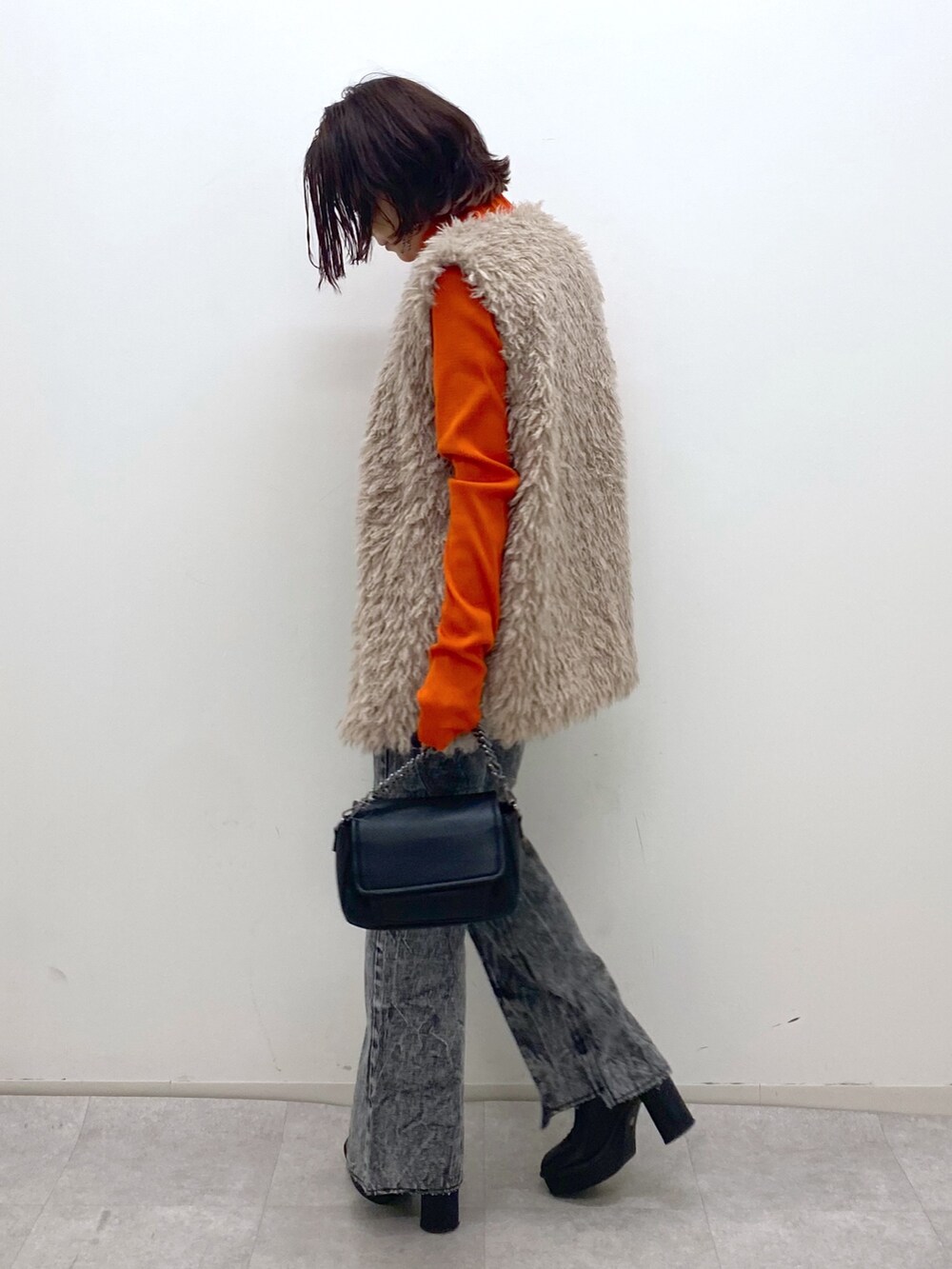ブラック系のデニムパンツ、ブラック系のバッグ、ブラック系のブーツを着用したレディースの秋コーディネートの4枚目の写真