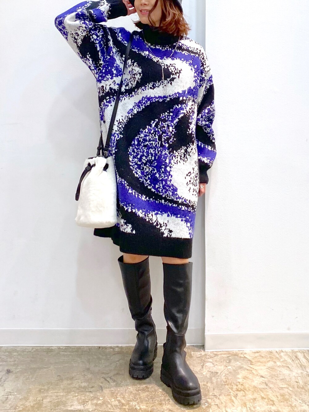 ブラック系のワンピース、ホワイト系のショルダーバッグ、ブラック系のブーツを着用したレディースの冬コーディネートの4枚目の写真