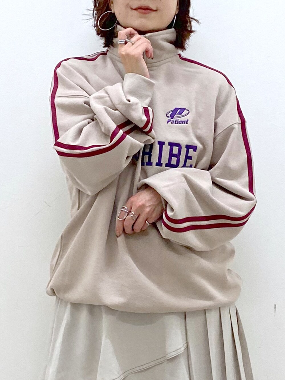 ベージュ系のスウェット、グレー系のスカート、ブラック系のブーツを着用したレディースの秋コーディネートの2枚目の写真