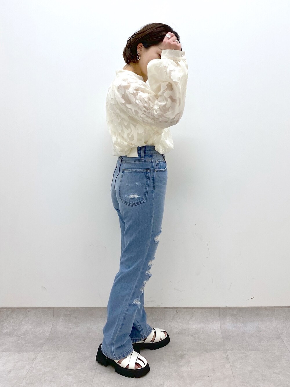 ブルー系のパンツ、ホワイト系のトップス、ホワイト系のサンダルを着用したレディースの春コーディネートの2枚目の写真