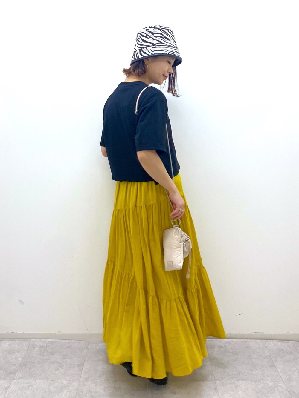 ブラック系のトップス、イエロー系のスカート、ベージュ系のショルダーバッグを着用したレディースの夏コーディネートの3枚目の写真