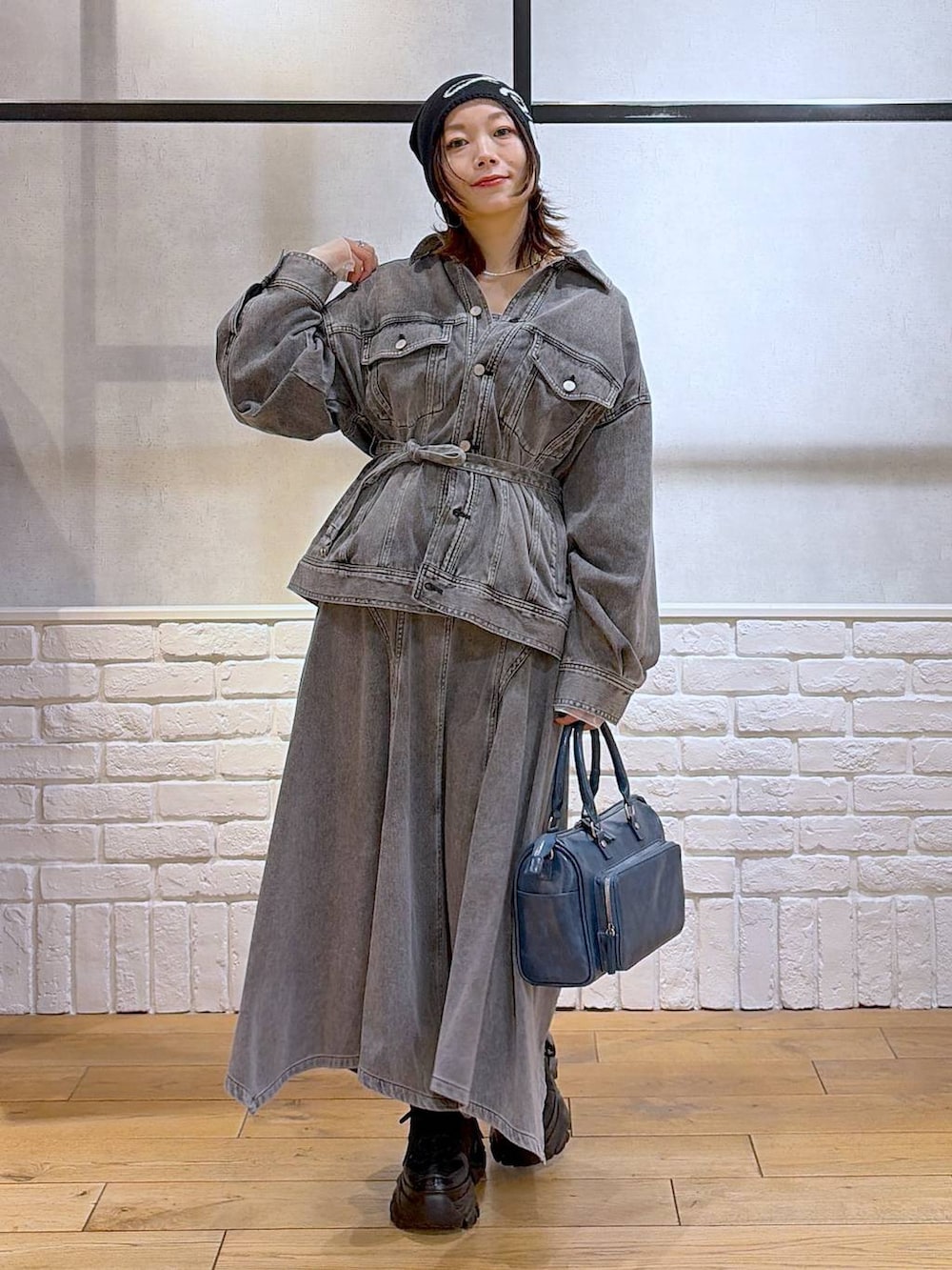 ブラック系のスニーカー、ブルー系のハンドバッグ、ブラック系のブルゾンを着用したレディースの冬コーディネートの3枚目の写真