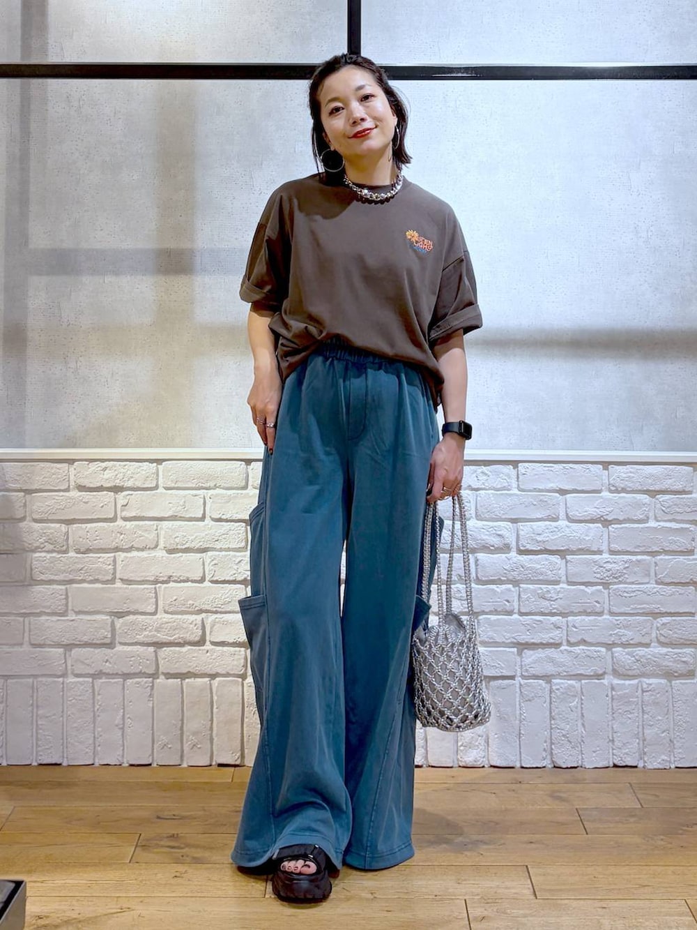 シルバー系のショルダーバッグ、ブラック系のサンダル、ブラウン系のTシャツ/カットソーを着用したレディースの春コーディネートの4枚目の写真