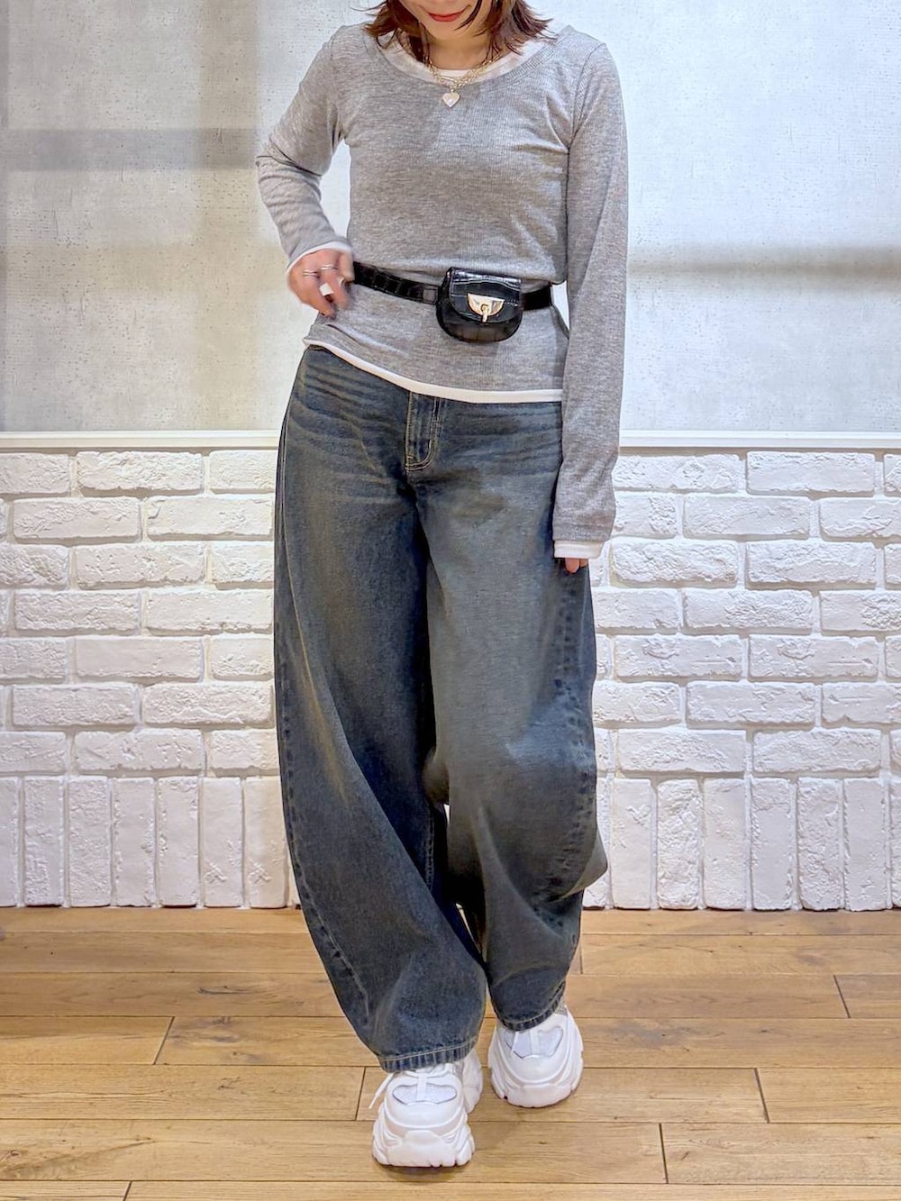 ホワイト系のスニーカー、ブラック系のボディバッグ/ウエストポーチ、ブルー系のデニムパンツを着用したレディースの冬コーディネートの3枚目の写真