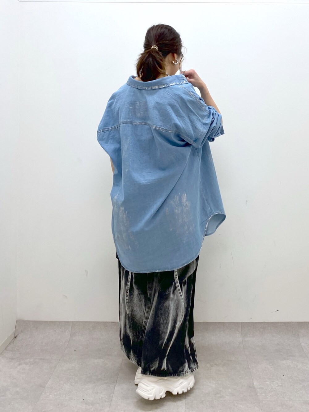 ブラック系のデニムパンツ、ホワイト系のスニーカー、ブラック系のワンピースを着用したレディースの春コーディネートの6枚目の写真