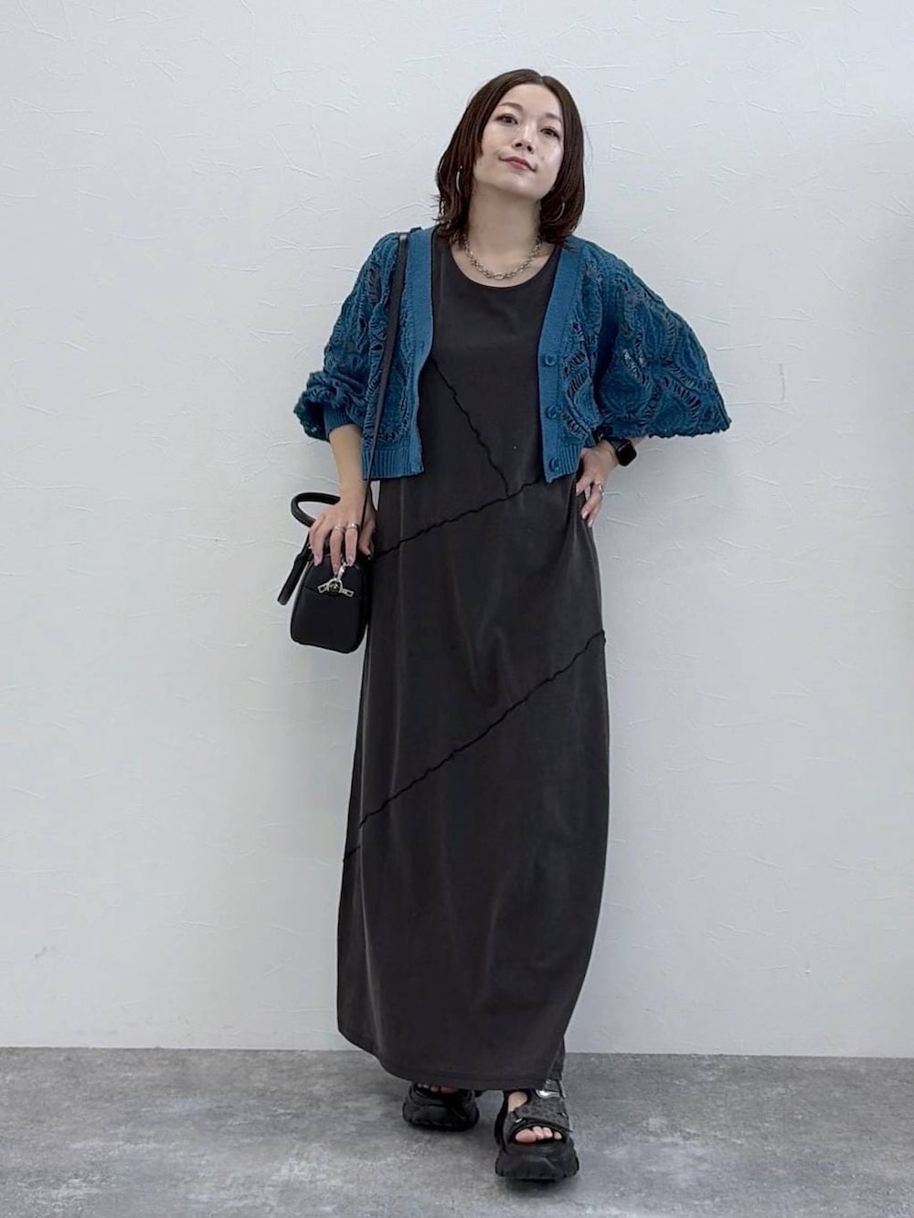 ブラック系のワンピース、ブルー系のカーディガン/ボレロ、ブラック系のボストンバッグを着用したレディースの春コーディネートの8枚目の写真