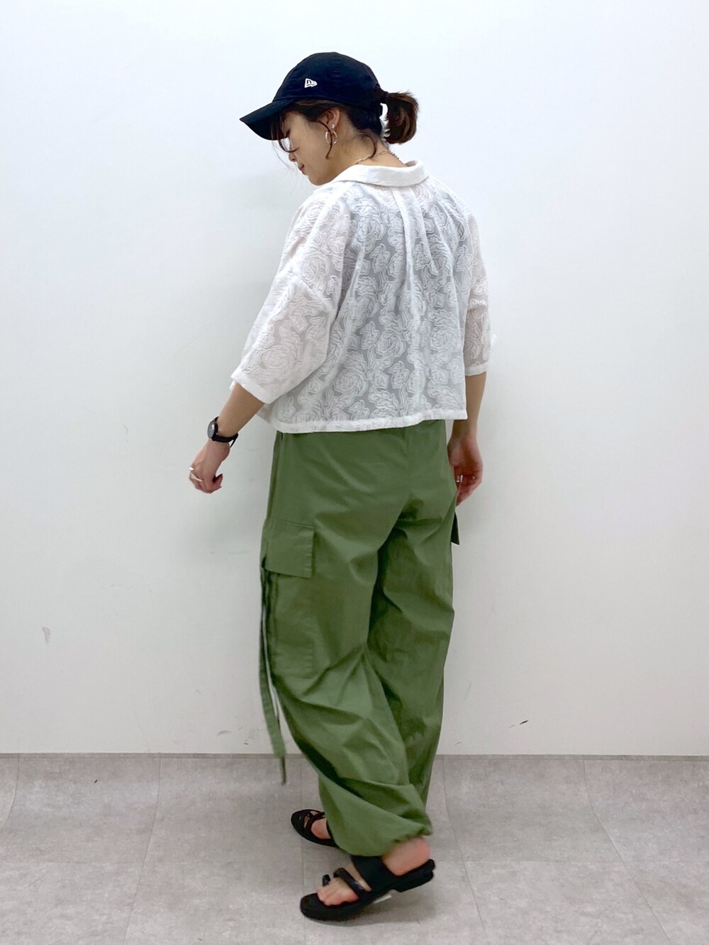 グリーン系のカーゴパンツ、ブラック系のサンダル、ブラック系のトップスを着用したレディースの夏コーディネートの3枚目の写真