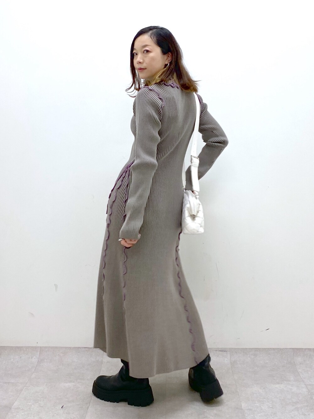 ブラウン系のワンピース、ホワイト系のショルダーバッグ、ブラック系のブーツを着用したレディースの秋コーディネートの6枚目の写真