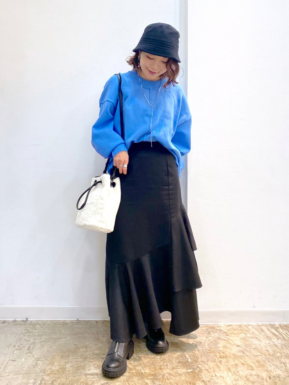 ホワイト系のショルダーバッグ、ブルー系のニット/セーター、ブラック系のスカートを着用したレディースの秋コーディネートの4枚目の写真