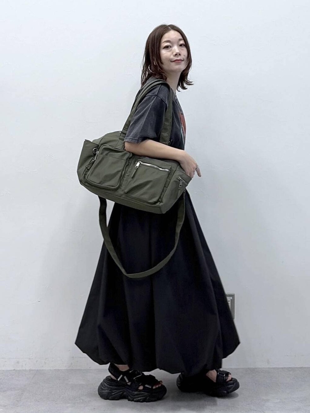 グリーン系のボストンバッグ、ブラック系のサンダル、ブラック系のスカートを着用したレディースの春コーディネートの8枚目の写真