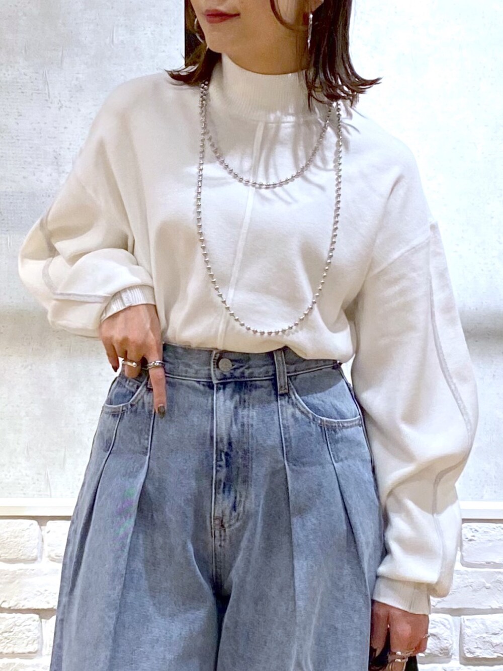 ホワイト系のニット/セーター、ブルー系のデニムパンツ、ブラック系のショルダーバッグを着用したレディースの冬コーディネートの2枚目の写真