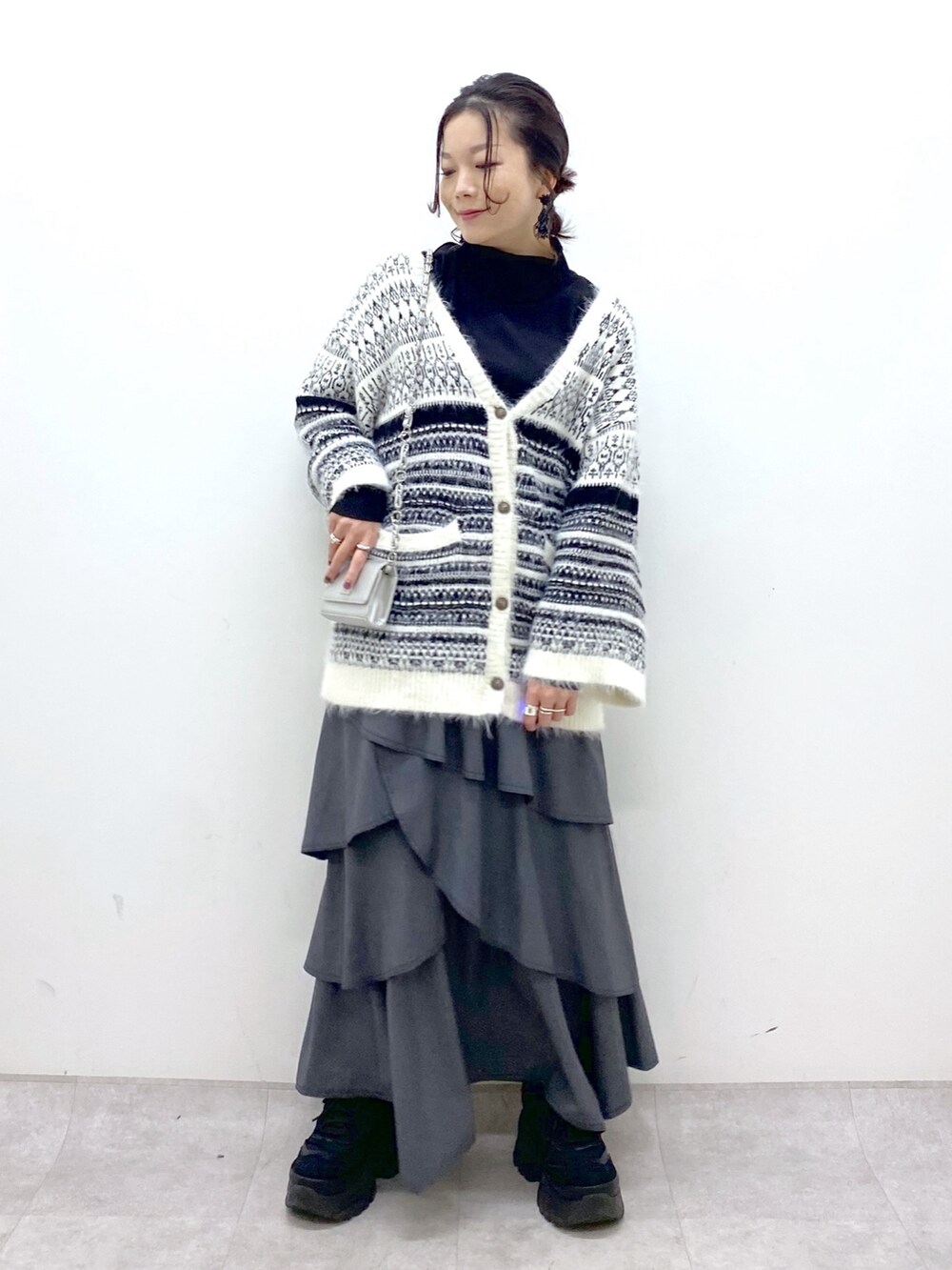 ホワイト系のカーディガン/ボレロ、グレー系のスカート、ブラック系のスニーカーを着用したレディースの冬コーディネートの9枚目の写真