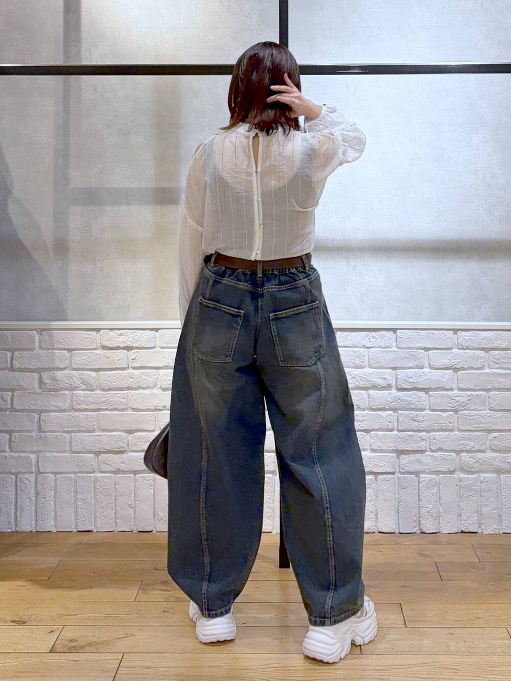 ホワイト系のスニーカー、ブルー系のデニムパンツ、ブラウン系のハンドバッグを着用したレディースの春コーディネートの6枚目の写真