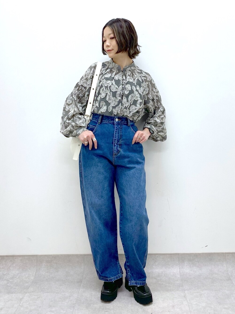 ブルー系のパンツ、グレー系のトップス、ホワイト系のショルダーバッグを着用したレディースの春コーディネートの5枚目の写真