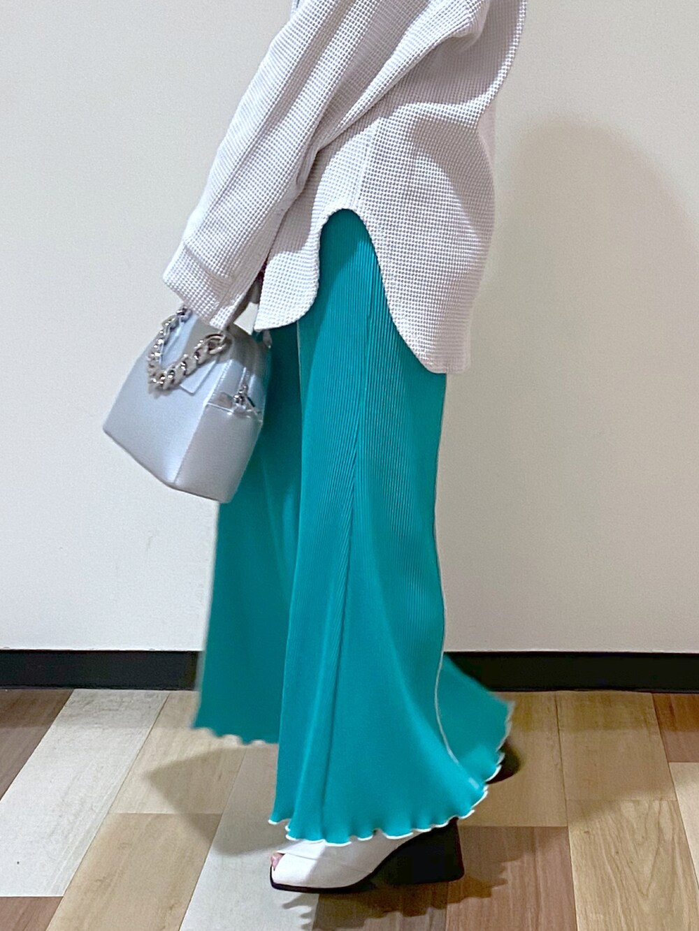 シルバー系のショルダーバッグ、グリーン系のスカート、ホワイト系のパンプスを着用したレディースの冬コーディネートの4枚目の写真