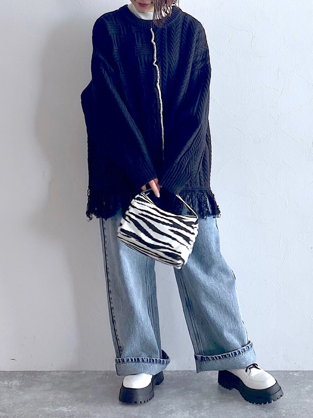 ブラック系のニット/セーター、ブルー系のデニムパンツ、ホワイト系のブーツを着用したレディースの夏コーディネートの5枚目の写真