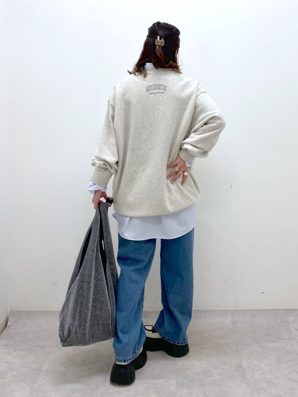 ベージュ系のスウェット、ブルー系のデニムパンツ、ブラック系のトートバッグを着用したレディースの冬コーディネートの6枚目の写真