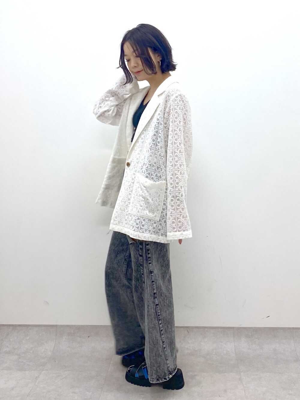 ホワイト系のテーラードジャケット、ブラック系のパンツ、ブラック系のサンダルを着用したレディースの春コーディネートの2枚目の写真