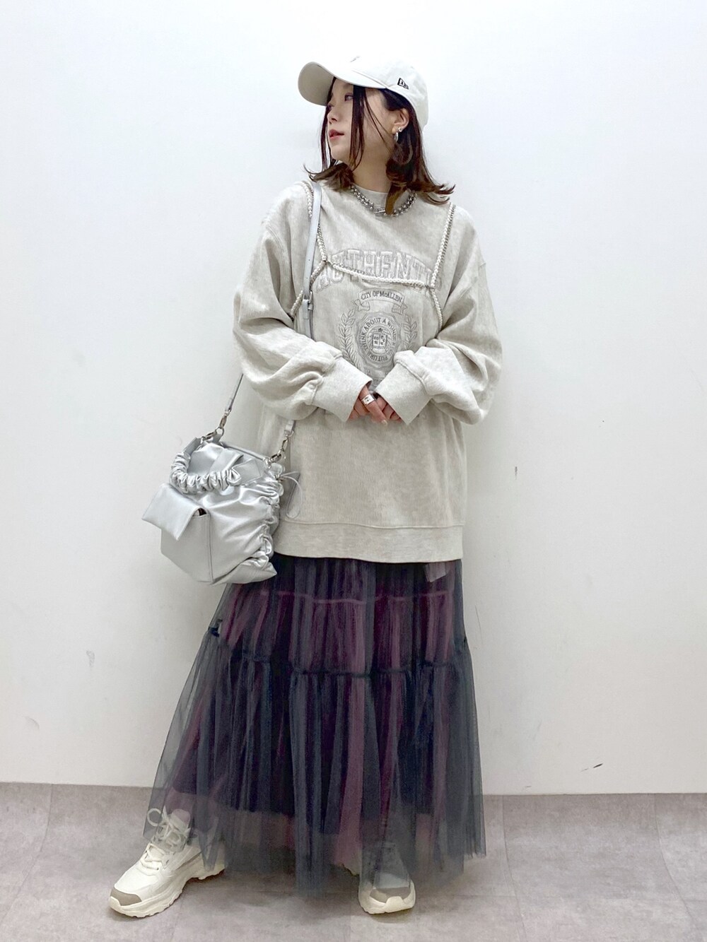 ベージュ系のスウェット、シルバー系のショルダーバッグ、グレー系のスカートを着用したレディースの春コーディネートの4枚目の写真